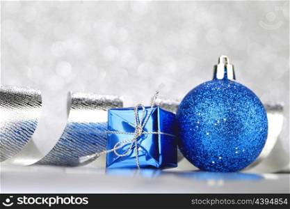 Christmas decoration ball and ribbon on silver glitter background