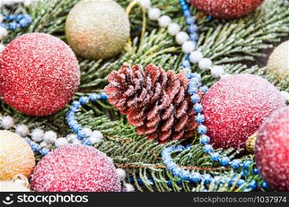 Christmas decoration baubles with branches of fir tree on wooden background with snowfall