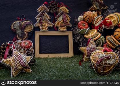 Christmas decoration, Brown natural pine cones and variety of fruits with Empty wooden frame for work about design element on lawn and dark background, Copy Space.