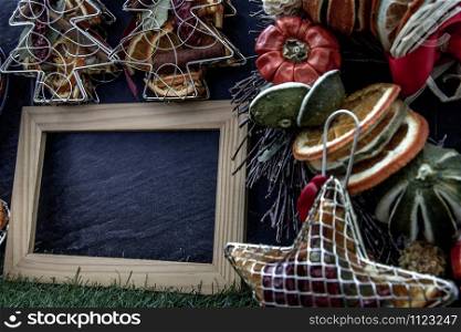 Christmas decoration, Brown natural pine cones and variety of fruits with Empty wooden frame for work about design element on lawn and dark background, Copy Space.