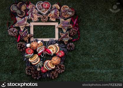 Christmas decoration, Brown natural pine cones and variety of fruits with Empty wooden frame for work about design element on lawn background, Copy Space.