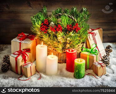 Christmas decoration burning candles and gift boxes. Christmas tree branches in basket. Vintage style toned picture with light effects. Vibrant colors