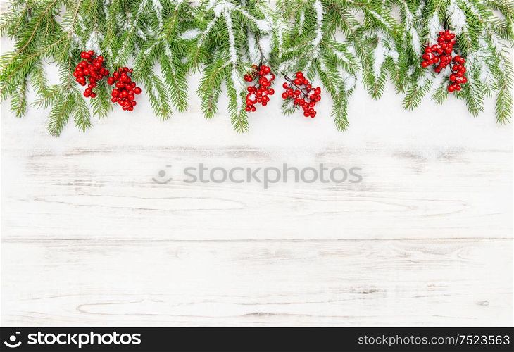 Christmas decoration. Coniferous tree branches with red berries on wooden background