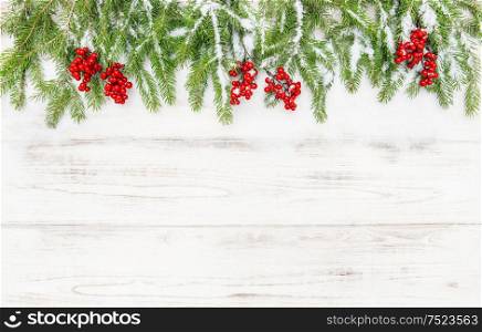 Christmas decoration. Coniferous tree branches with red berries on wooden background