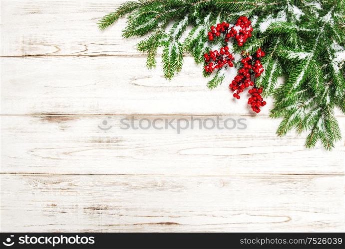 Christmas decoration. Evergreen tree branch with red berries on wooden background