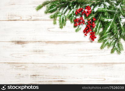 Christmas decoration. Evergreen tree branch with red berries on wooden background