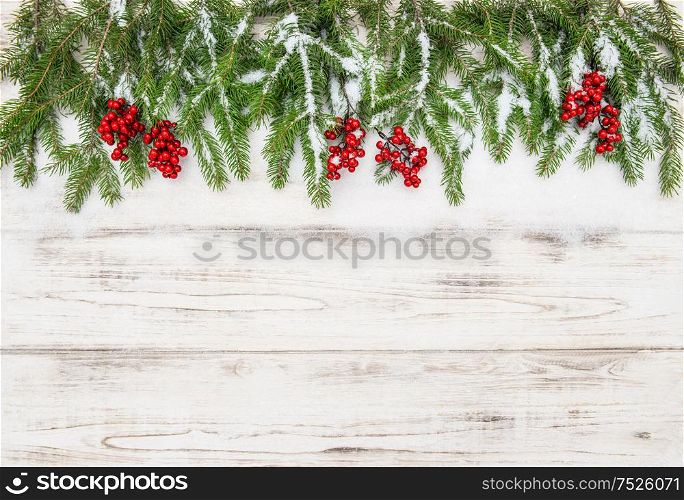 Christmas decoration. Evergreen tree branch with red berries on wooden background