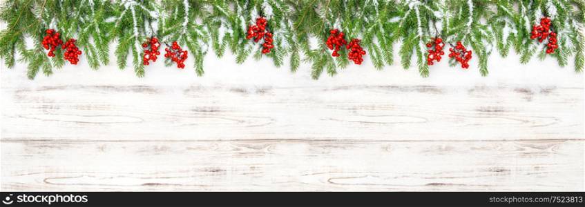 Christmas decoration. Floral holidays banner. Evergreen tree branches with red berries on wooden background
