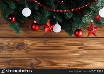 Christmas decoration frame on wooden background, fir tree branch, red and white baubles. Christmas decoration frame