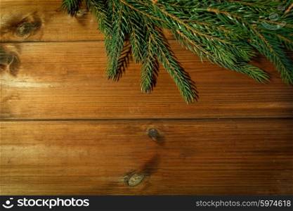 christmas, decoration, holidays and advertisement concept - close up of natural fir branch on blank brown wooden board