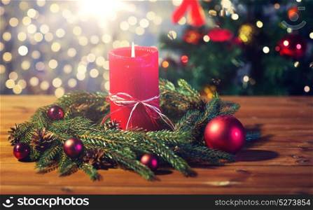 christmas, decoration, holidays and advertisement concept - close up of natural green fir branch wreath with red burning candle on wooden board. fir branch wreath with candle on wooden table