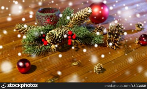 christmas, decoration, holidays and new year concept - close up of natural fir branch decoration with fir-cones, balls and candle in lantern on wooden table. christmas fir branch decoration and candle lantern