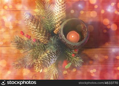 christmas, decoration, holidays and new year concept - close up of natural fir branch decoration and fir-cone and candle in lantern on wooden table over lights