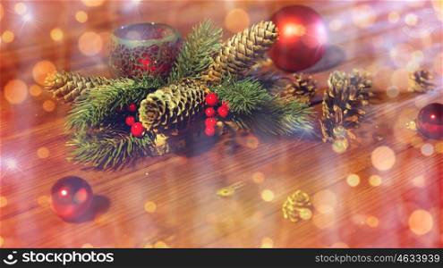 christmas, decoration, holidays and new year concept - close up of natural fir branch decoration with fir-cones, balls and candle in lantern on wooden table over lights