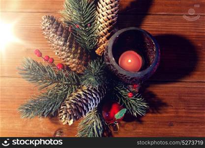 christmas, decoration, holidays and new year concept - close up of natural fir branch decoration and fir-cone and candle in lantern on wooden table. christmas fir branch decoration and candle lantern