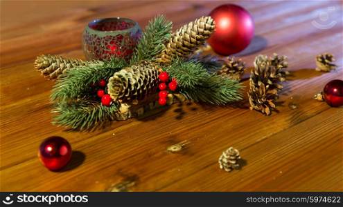 christmas, decoration, holidays and new year concept - close up of natural fir branch decoration with fir-cones, balls and candle in lantern on wooden table