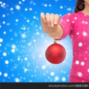 christmas, decoration, holidays and people concept - close up of woman in pink sweater holding christmas ball blue snowy background