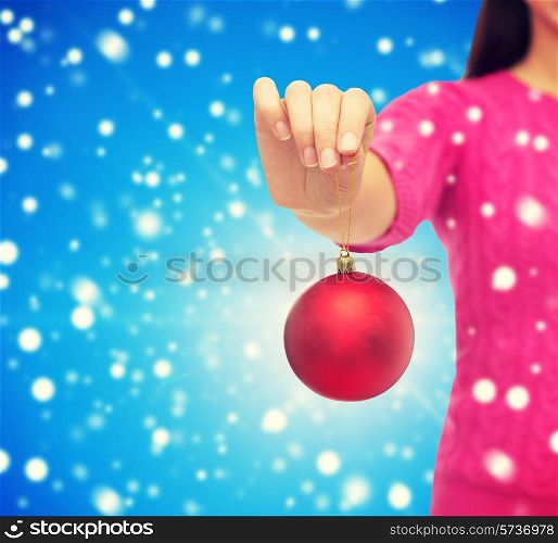 christmas, decoration, holidays and people concept - close up of woman in pink sweater holding christmas ball blue snowy background