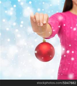 christmas, decoration, holidays and people concept - close up of woman in pink sweater holding christmas ball over blue lights background
