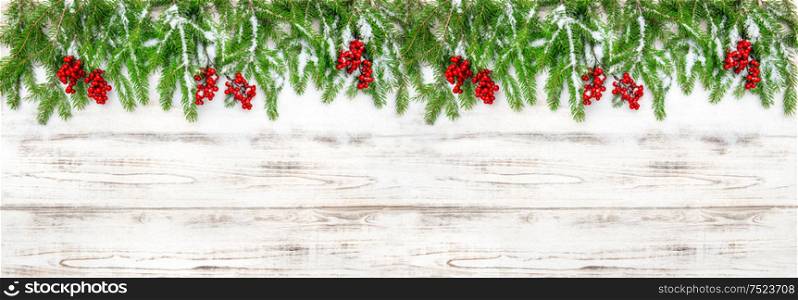 Christmas decoration. Holidays banner. Pine tree branches and red berries on wooden background