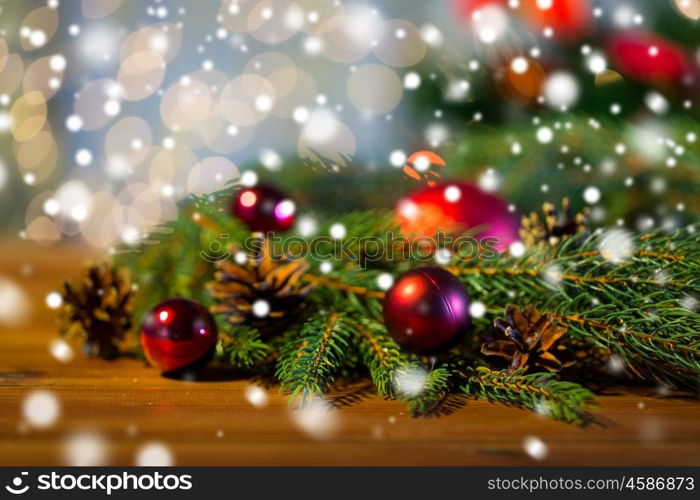 christmas decoration, holidays, new year and decor concept - close up of natural fir branch, ball and pinecone on wooden table