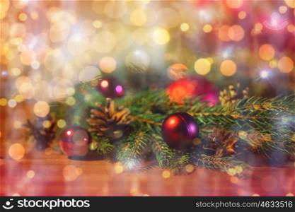 christmas decoration, holidays, new year and decor concept - close up of natural fir branch, ball and pinecone over lights