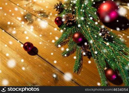 christmas decoration, holidays, new year and decor concept - close up of natural fir branch, ball and pinecone on wooden table