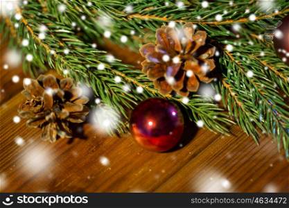 christmas decoration, holidays, new year and decor concept - close up of natural fir branch, ball and pinecone on wooden table