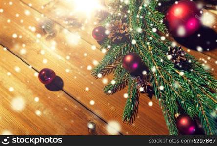 christmas decoration, holidays, new year and decor concept - close up of natural fir branch, ball and pinecone on wooden table. fir branch with christmas ball and pinecones