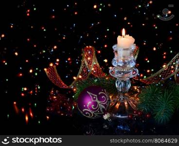 Christmas decoration in red tones with a burning candle on a black background