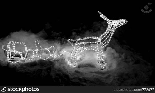 Christmas decoration isolated on black background. Deer and sleigh made of glowing garland. New year illumination. Christmas decoration.
