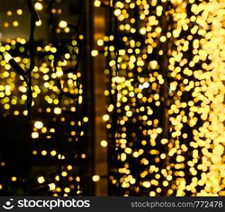 Christmas decoration made of glowing garland. New year illumination. Bright yellow and golden glitter lights background. Defocused.