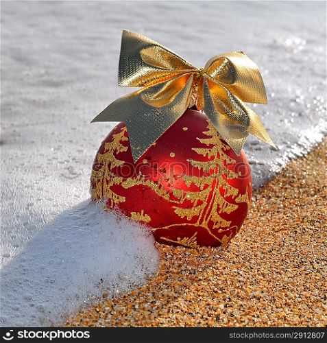 Christmas decoration on yellow beach sand against ocean wave