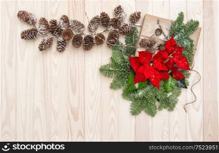 Christmas decoration. Pine branches, wrapped gift and poinsettia flowers on wooden background