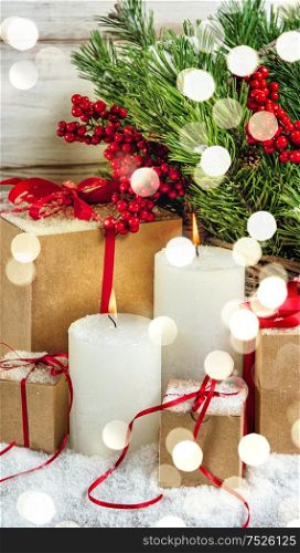 Christmas decoration with burning candles and gifts. Retro style toned picture with light effects