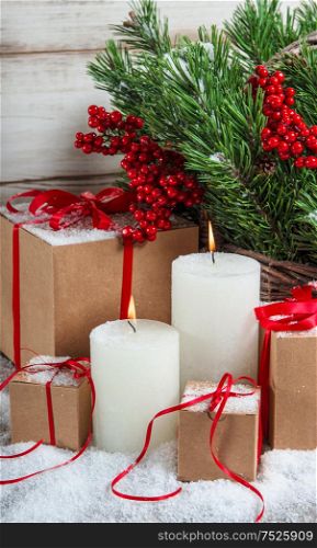 Christmas decoration with candles and gifts. Christmas tree branches with red berries