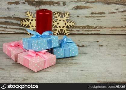 Christmas decoration with four Christmas gifts, red candle and two wooden decorative snowflakes on vintage background. Close,horizontal view.