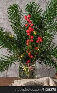 Christmas decoration with pine branches in a jar, lights and red holly balls. Christmas tree wallpaper for card or other design in Christmas concept.