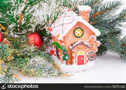 Christmas decoration with red balls, fir-tree branch and toy house.