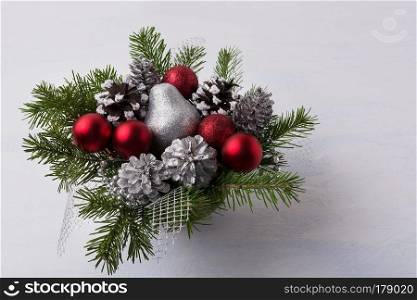 Christmas decoration with red glitter ornaments and silver mash. Christmas table centerpiece with pine cones and silver pear. 