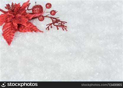 Christmas decoration with red poinsettia flower on a white snow background, with space for text