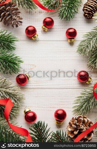 Christmas decoration with red ribbon making a frame on a white wooden background. Christmas themes. Flat lay, copy space