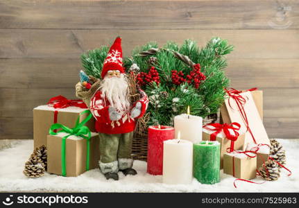 Christmas decoration with Santa Claus, burning candles and gift boxes. Fir tree branches in basket. No name toy mass-produced