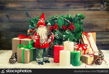 Christmas decoration with Santa Claus, gift boxes, burning candles. Vintage style toned picture