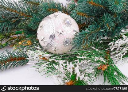 Christmas decoration with white ball and fir-tree branch.
