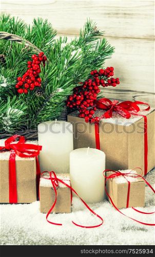 Christmas decoration with white candles and gift box. Christmas tree branches. Vintage style toned picture