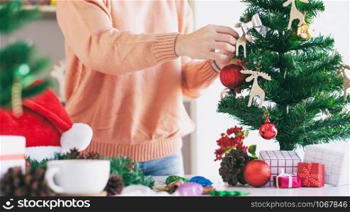 Christmas decoration. Woman hands decorating the Christmas tree and Christmas wreath.