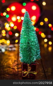 Christmas decorations against blurred background and out of focus lights. Small Christmas tree with gift box