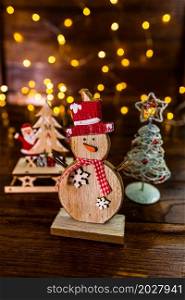 Christmas decorations against blurred background. Small wooden snowman.