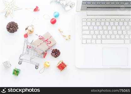 Christmas decorations and gift boxes in shopping cart and laptop, Online shopping concept, top view